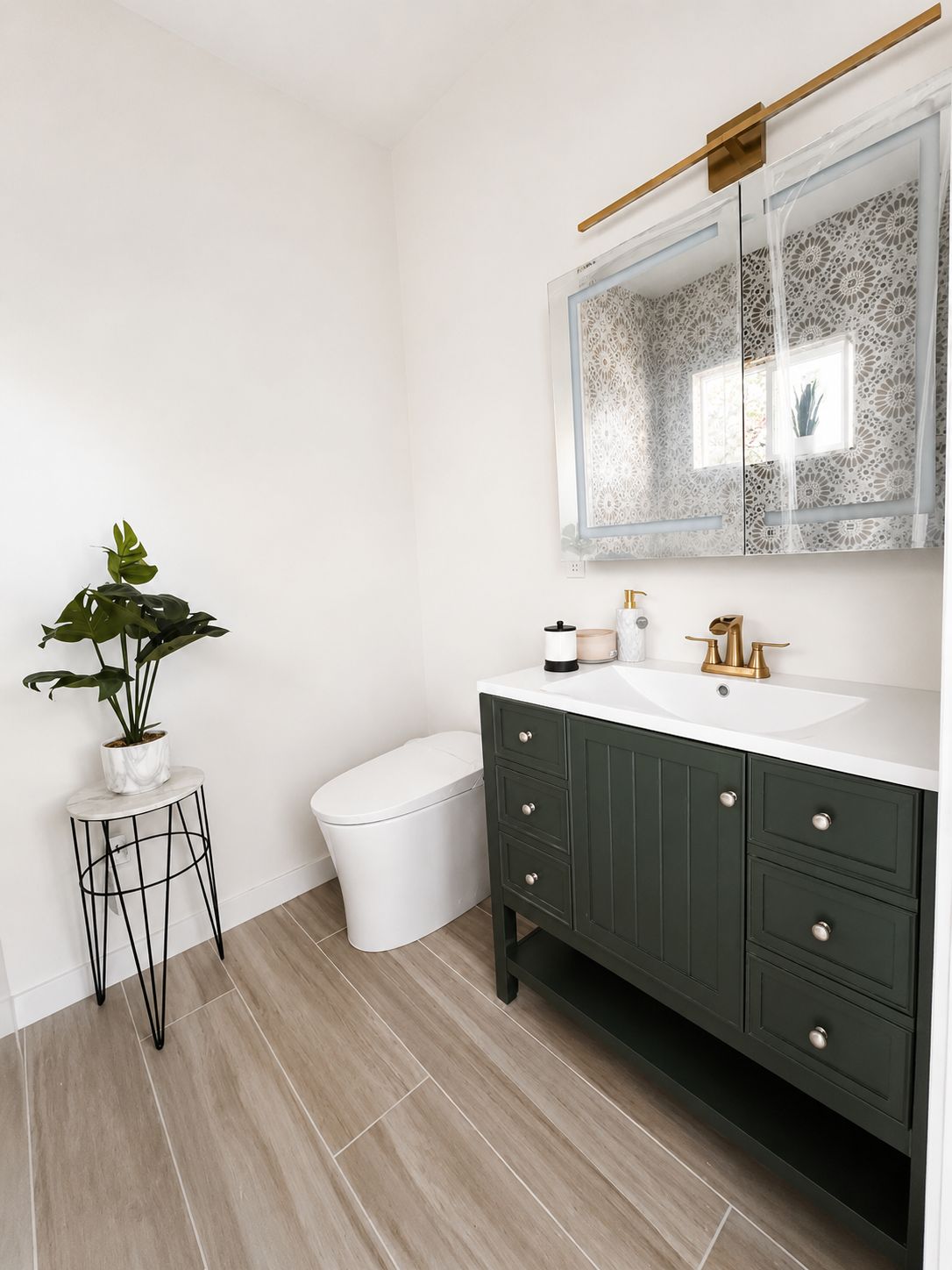 Bathroom vanity with dark green cabinetry and brass fixtures