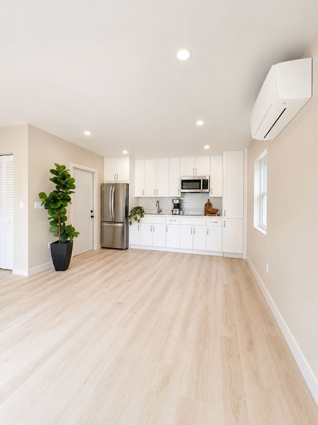 Open living space with mini-split unit and kitchen in the background