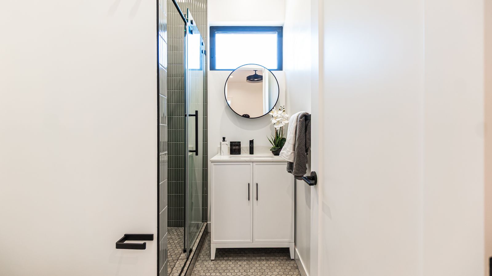 Bathroom vanity with round mirror and glass shower