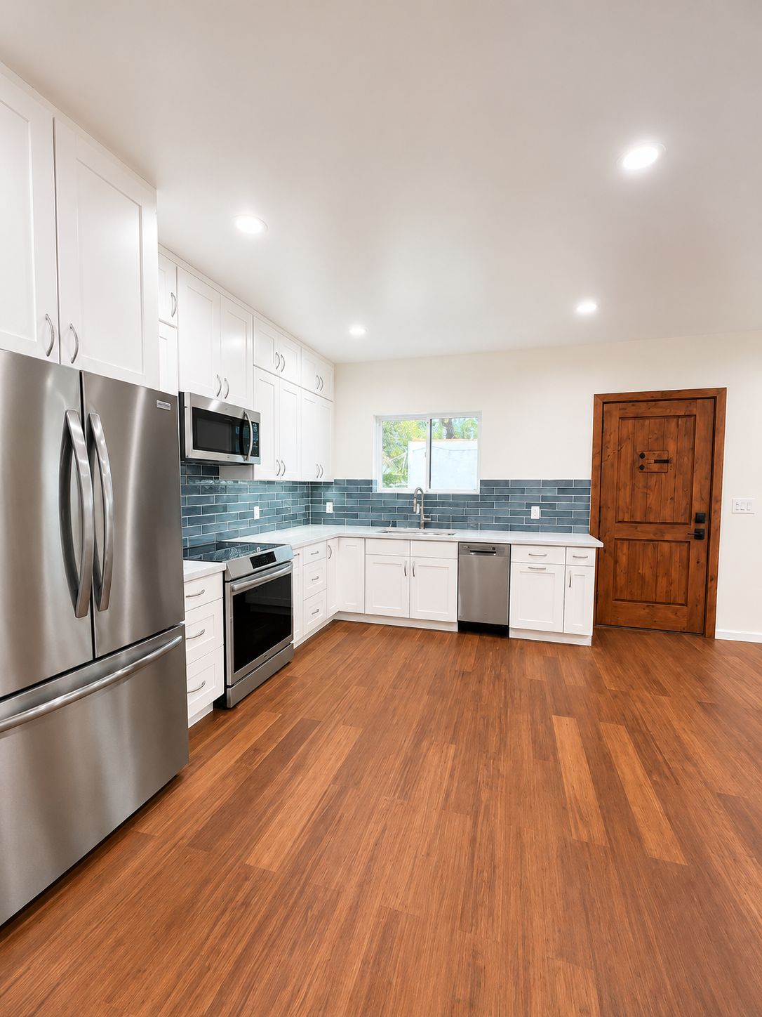 Kitchen with white cabinetry, blue subway tile backsplash, and stainless appliances